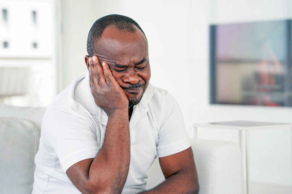 A frustrated man sits around a table filled with scattered documents,