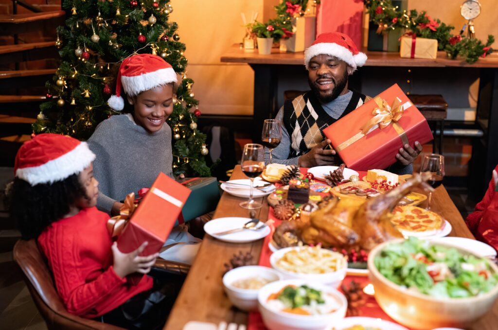 Christmas budgeting tips. A family exchanging Christmas gifts around a decorated tree, symbolizing a joyful and budget-conscious holiday.