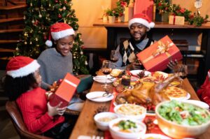 Christmas budgeting tips. A family exchanging Christmas gifts around a decorated tree, symbolizing a joyful and budget-conscious holiday.